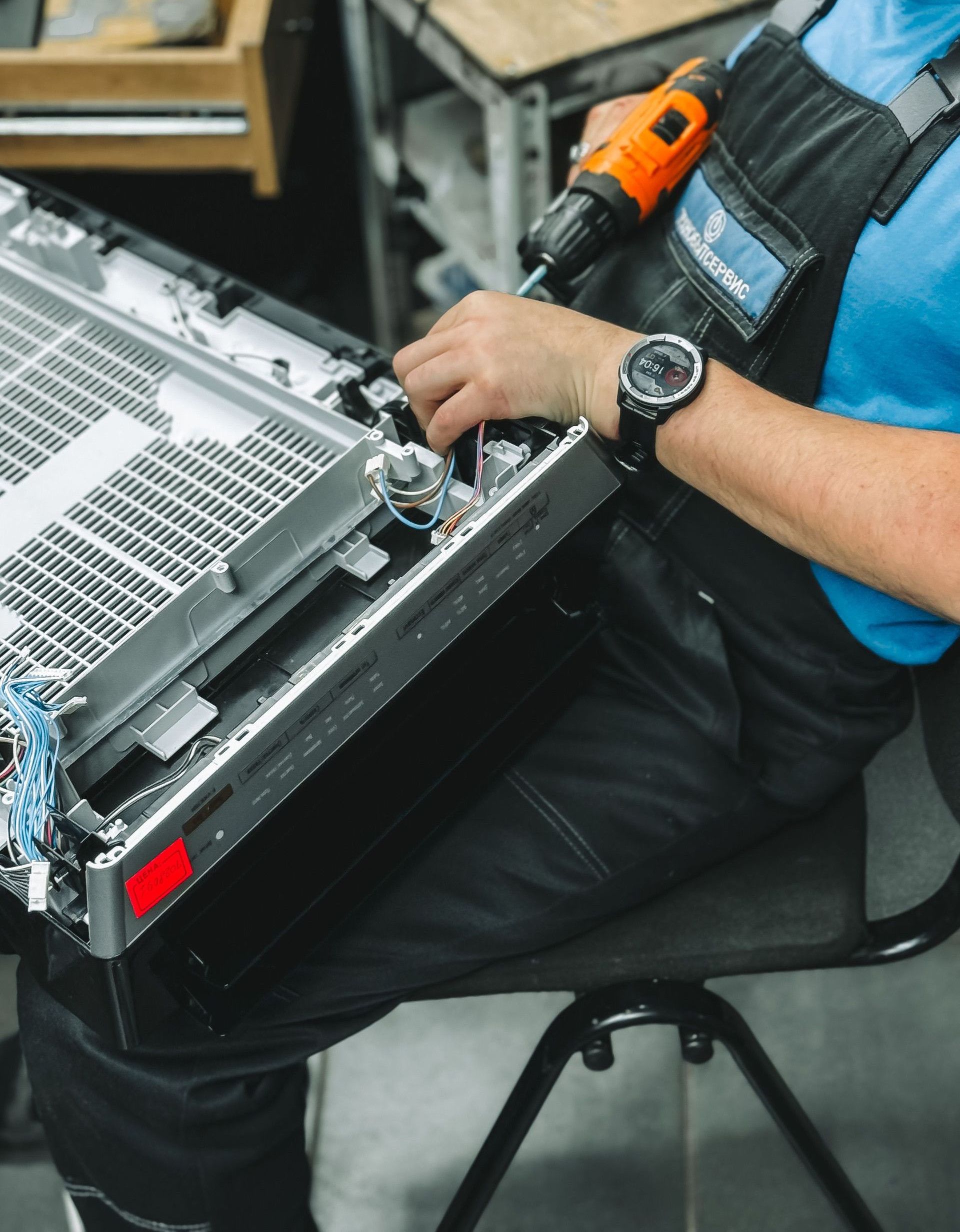 Focused technician working with tools on electronic equipment in indoor workshop setting.